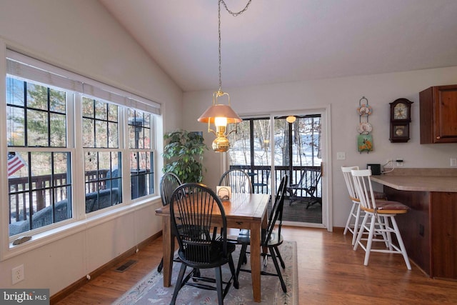 dining area featuring lofted ceiling, hardwood / wood-style flooring, and plenty of natural light