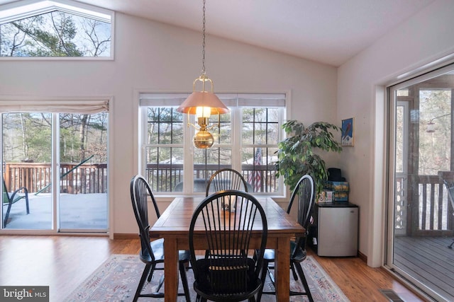 dining space with vaulted ceiling and light hardwood / wood-style floors