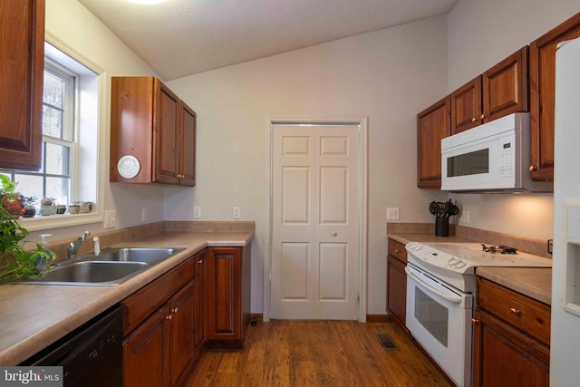 kitchen featuring sink, white appliances, vaulted ceiling, and light hardwood / wood-style flooring