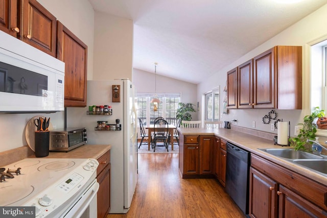 kitchen featuring white appliances, vaulted ceiling, light hardwood / wood-style floors, sink, and decorative light fixtures