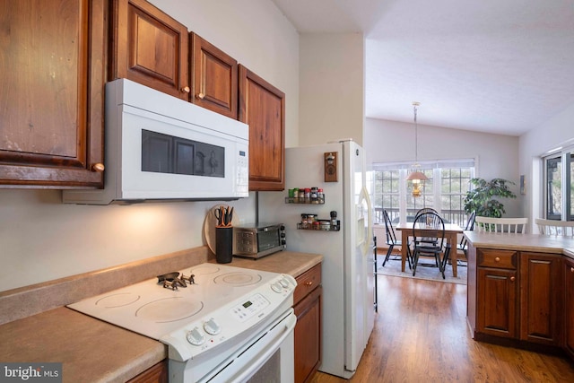 kitchen with white appliances, light hardwood / wood-style floors, decorative light fixtures, and vaulted ceiling