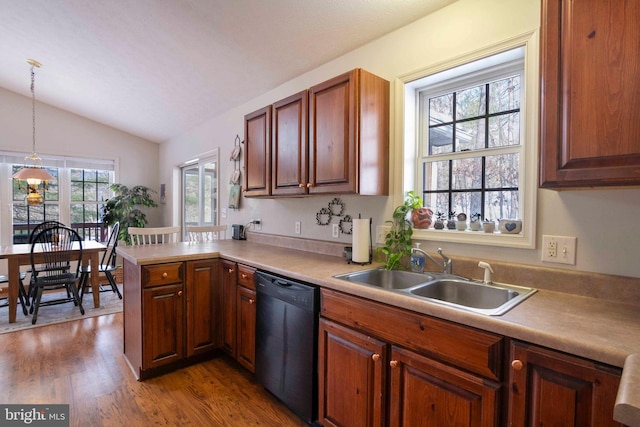 kitchen featuring sink, decorative light fixtures, black dishwasher, lofted ceiling, and kitchen peninsula