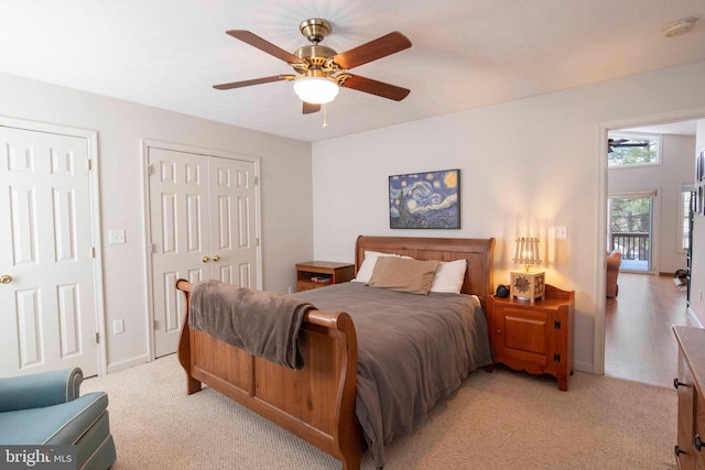 bedroom with multiple closets, light carpet, and ceiling fan