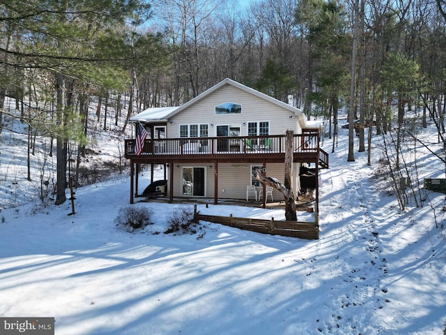 snow covered house featuring a wooden deck