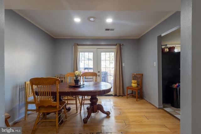 dining area with crown molding, french doors, and light wood-type flooring