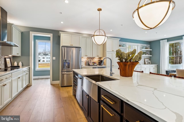 kitchen with tasteful backsplash, light hardwood / wood-style flooring, light stone countertops, pendant lighting, and appliances with stainless steel finishes