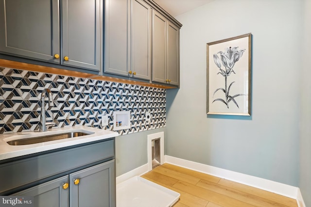 laundry area with sink, washer hookup, cabinets, and light hardwood / wood-style flooring