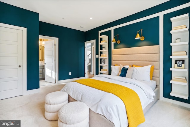 bedroom featuring light colored carpet and ensuite bathroom