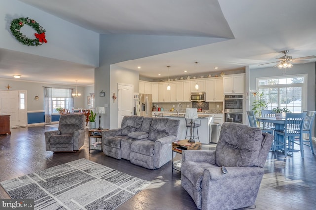 living room featuring ceiling fan with notable chandelier, lofted ceiling, dark hardwood / wood-style floors, and sink