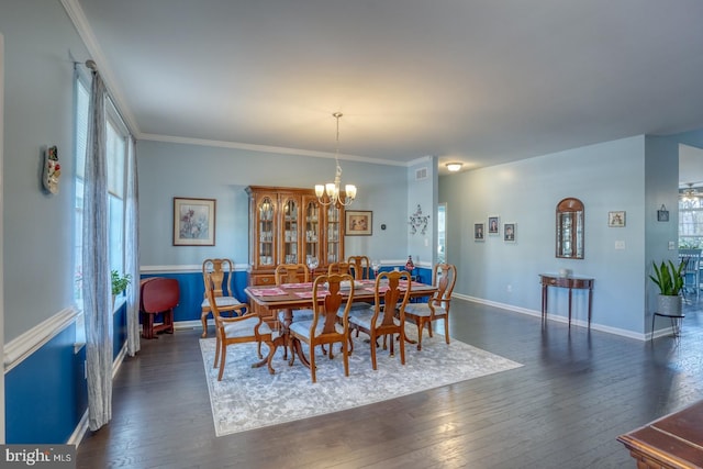 dining area with dark hardwood / wood-style flooring, ornamental molding, and a chandelier