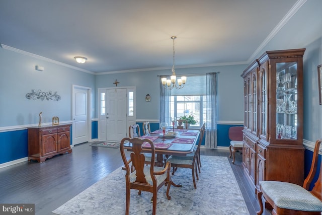 dining space with dark wood-type flooring, an inviting chandelier, and crown molding