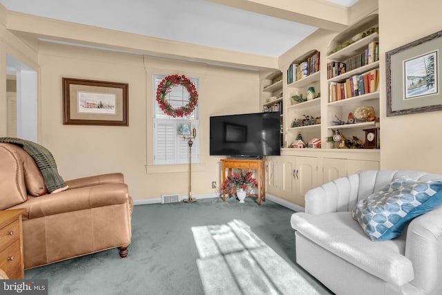 living room featuring built in shelves, carpet floors, and beamed ceiling