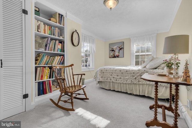 bedroom featuring light colored carpet, crown molding, and a textured ceiling