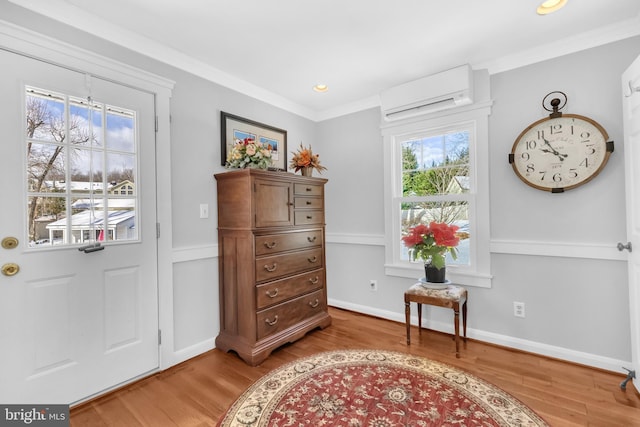 living area with a wall unit AC, crown molding, and wood-type flooring