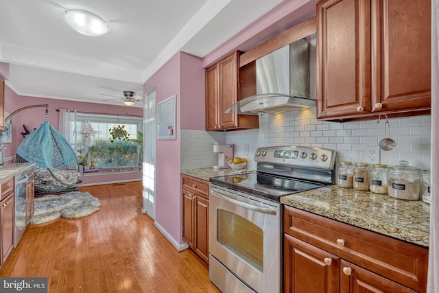 kitchen featuring stainless steel range with electric cooktop, decorative backsplash, wall chimney range hood, and light stone counters