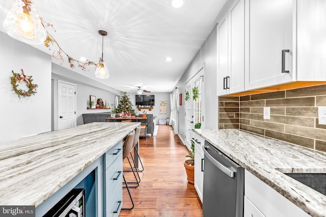 kitchen featuring a kitchen breakfast bar, ceiling fan, white cabinets, decorative light fixtures, and stainless steel dishwasher