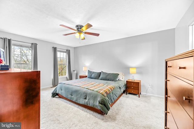 carpeted bedroom featuring ceiling fan and a textured ceiling