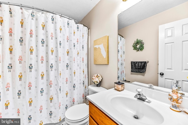 bathroom featuring toilet, a textured ceiling, and vanity