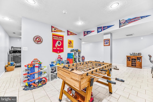 playroom with a textured ceiling and light tile patterned floors