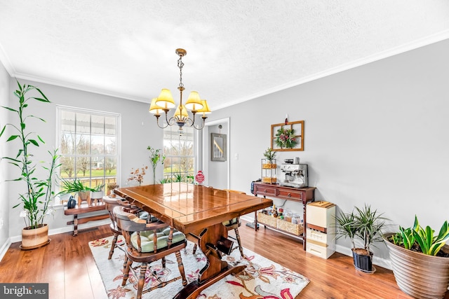 dining space featuring ornamental molding, light hardwood / wood-style floors, a textured ceiling, and a chandelier