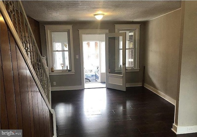 doorway to outside featuring a textured ceiling and dark hardwood / wood-style floors