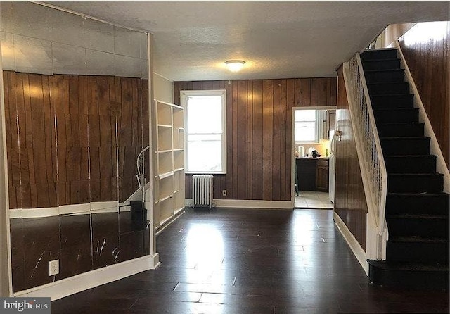 interior space featuring a textured ceiling, wood walls, and radiator