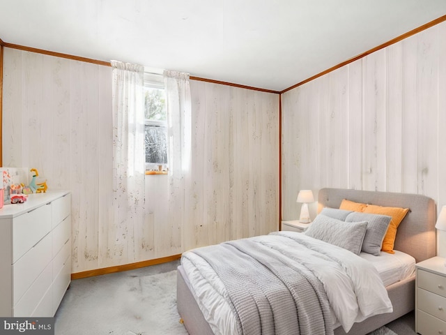 bedroom featuring ornamental molding, light colored carpet, and wood walls