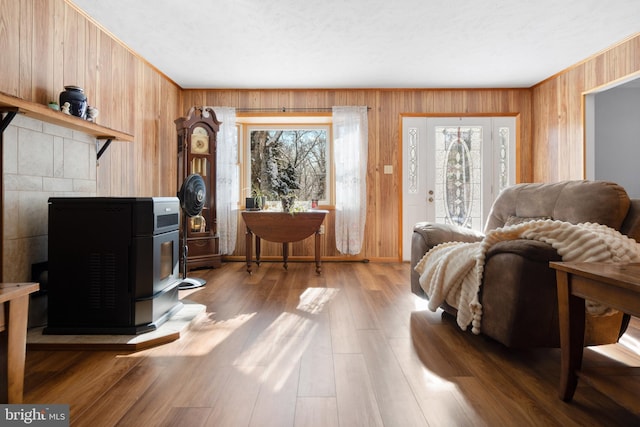 living room with wood walls, a wood stove, and hardwood / wood-style flooring