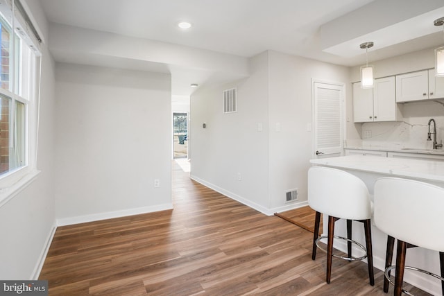 kitchen featuring white cabinetry, decorative backsplash, sink, dark hardwood / wood-style floors, and light stone counters