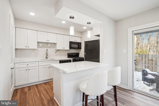 kitchen featuring white cabinetry, sink, decorative backsplash, and black appliances