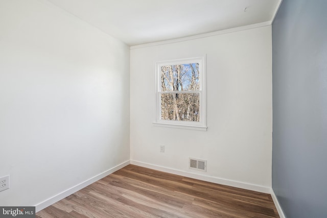 empty room featuring hardwood / wood-style flooring and ornamental molding