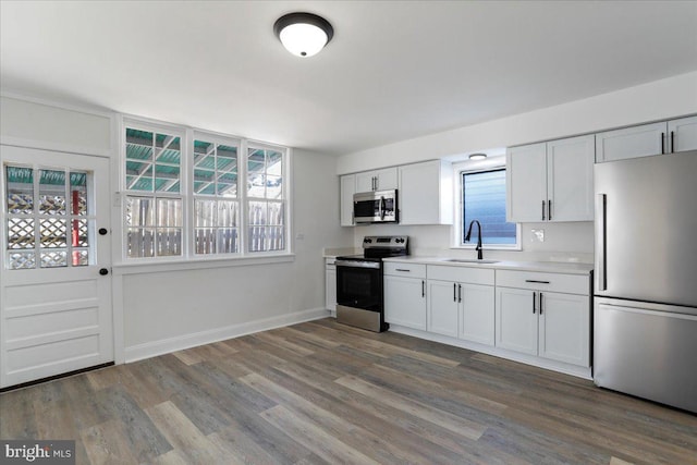 kitchen with sink, stainless steel appliances, white cabinets, and wood-type flooring