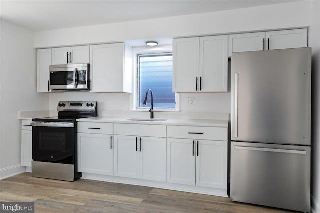 kitchen featuring sink, light hardwood / wood-style floors, white cabinets, and appliances with stainless steel finishes