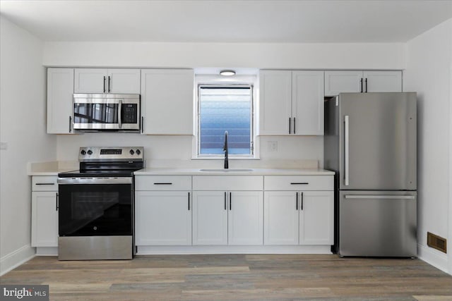 kitchen featuring sink, light hardwood / wood-style floors, white cabinetry, and appliances with stainless steel finishes