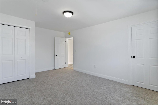 unfurnished bedroom with a closet and light colored carpet