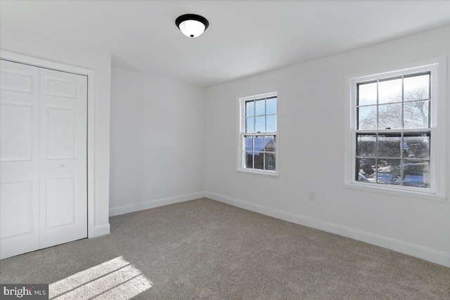 unfurnished bedroom featuring multiple windows, a closet, and carpet