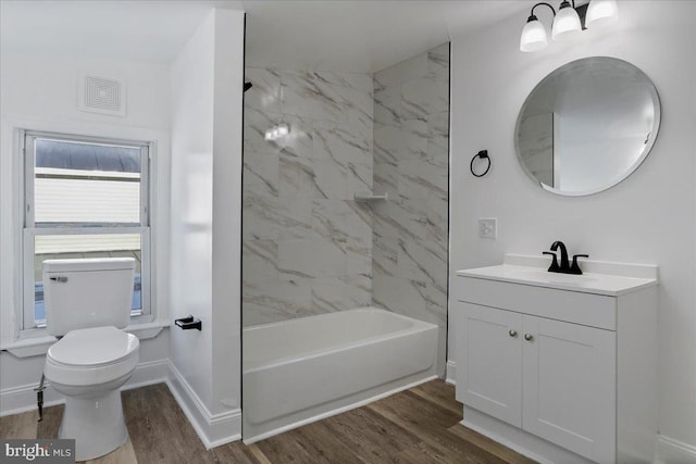 full bathroom with hardwood / wood-style floors, toilet, vanity, and tiled shower / bath combo