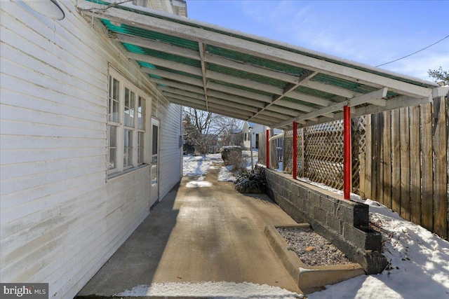 snow covered parking area with a carport