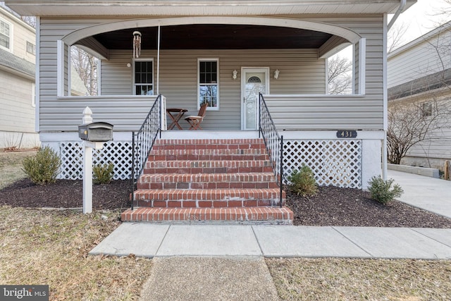 view of exterior entry with a porch and driveway