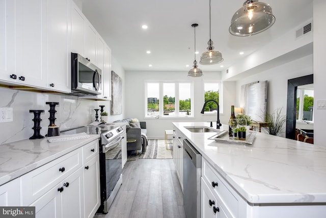 kitchen with white cabinets, sink, stainless steel appliances, and pendant lighting