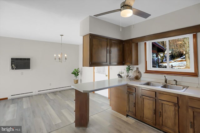 kitchen with baseboard heating, an AC wall unit, sink, light hardwood / wood-style flooring, and decorative light fixtures