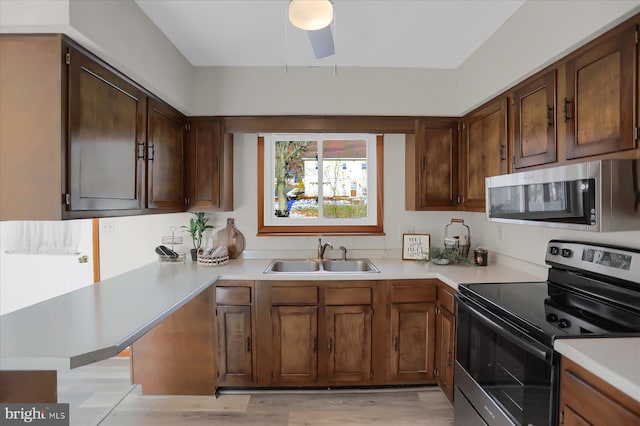 kitchen featuring kitchen peninsula, light wood-type flooring, appliances with stainless steel finishes, ceiling fan, and sink