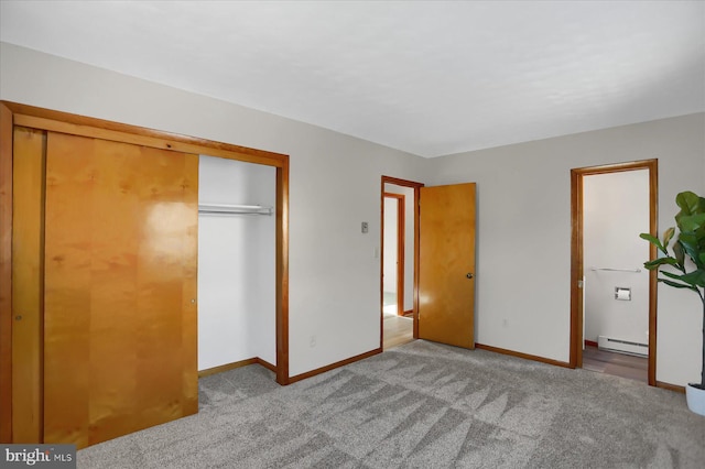 unfurnished bedroom with a closet, a baseboard heating unit, and light carpet