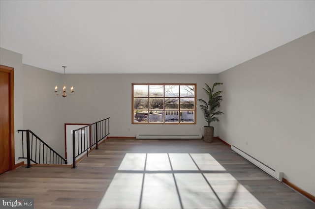 unfurnished room featuring a baseboard heating unit, an inviting chandelier, and hardwood / wood-style floors