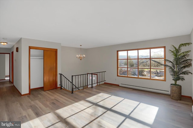 spare room with a baseboard heating unit, a chandelier, and light hardwood / wood-style floors