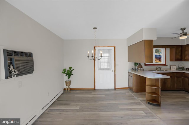 kitchen featuring sink, light hardwood / wood-style flooring, ceiling fan with notable chandelier, kitchen peninsula, and hanging light fixtures