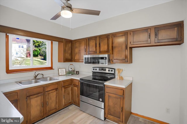 kitchen featuring light wood-type flooring, appliances with stainless steel finishes, ceiling fan, and sink