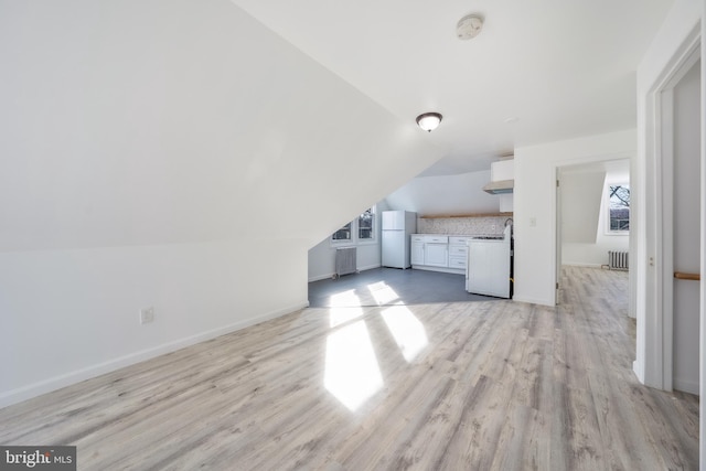 unfurnished living room with radiator, lofted ceiling, and light hardwood / wood-style flooring