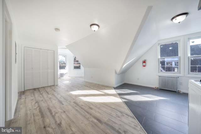 additional living space featuring lofted ceiling, radiator, and light hardwood / wood-style flooring