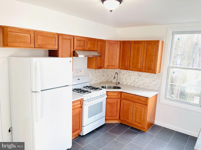 kitchen featuring white appliances, a healthy amount of sunlight, decorative backsplash, and sink